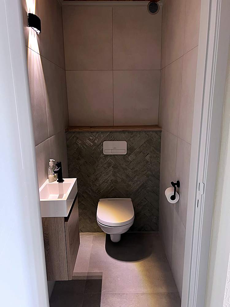 Toilet met groene wandtegels, hangtoilet en fonteintje